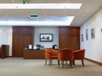 armchairs, table and reception in light, clean and empty office; TV on wall